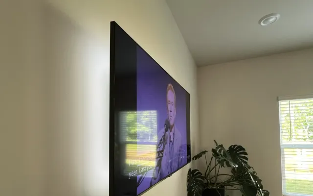 A wall-mounted TV below a sloped ceiling in a bright room