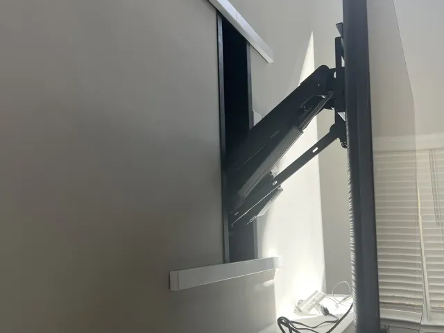 Side view of a TV on a full-motion arm, extended off a white wall