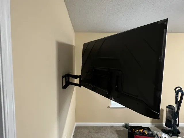 A TV on a full-motion arm swung out from a beige garage wall
