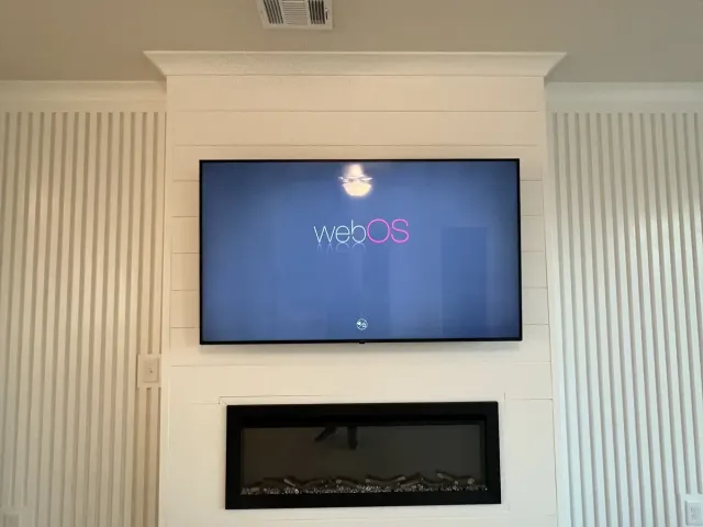 A TV on a white shiplap fireplace wall above a linear electric fireplace