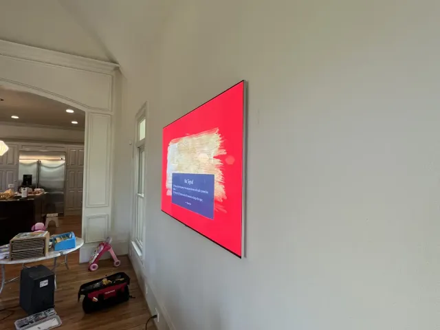 A TV on a flat mount on a cream living-room wall above a wood floor