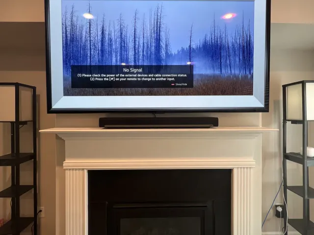 A Samsung Frame TV with a white bezel and a soundbar mounted above a white mantel fireplace