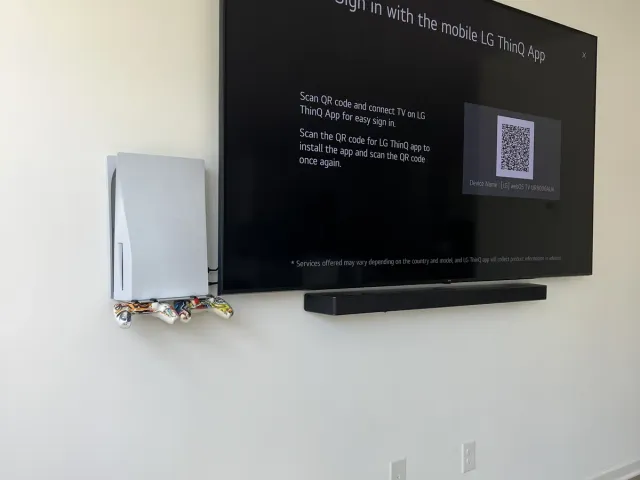 An LG TV with a soundbar under it on a white wall, the sign-in screen showing