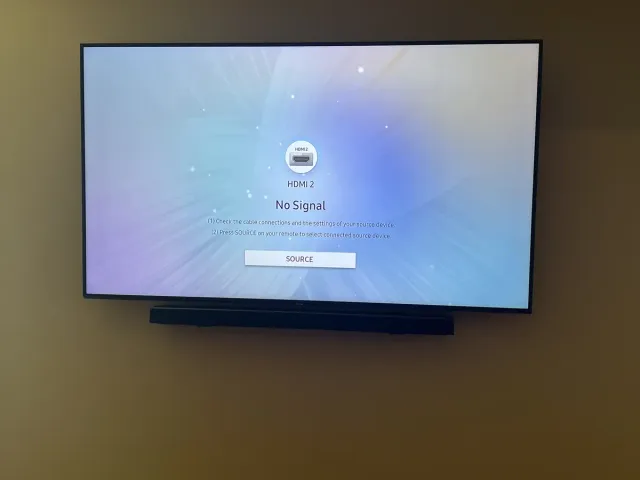 A Roku TV on a flat mount on a tan bedroom wall