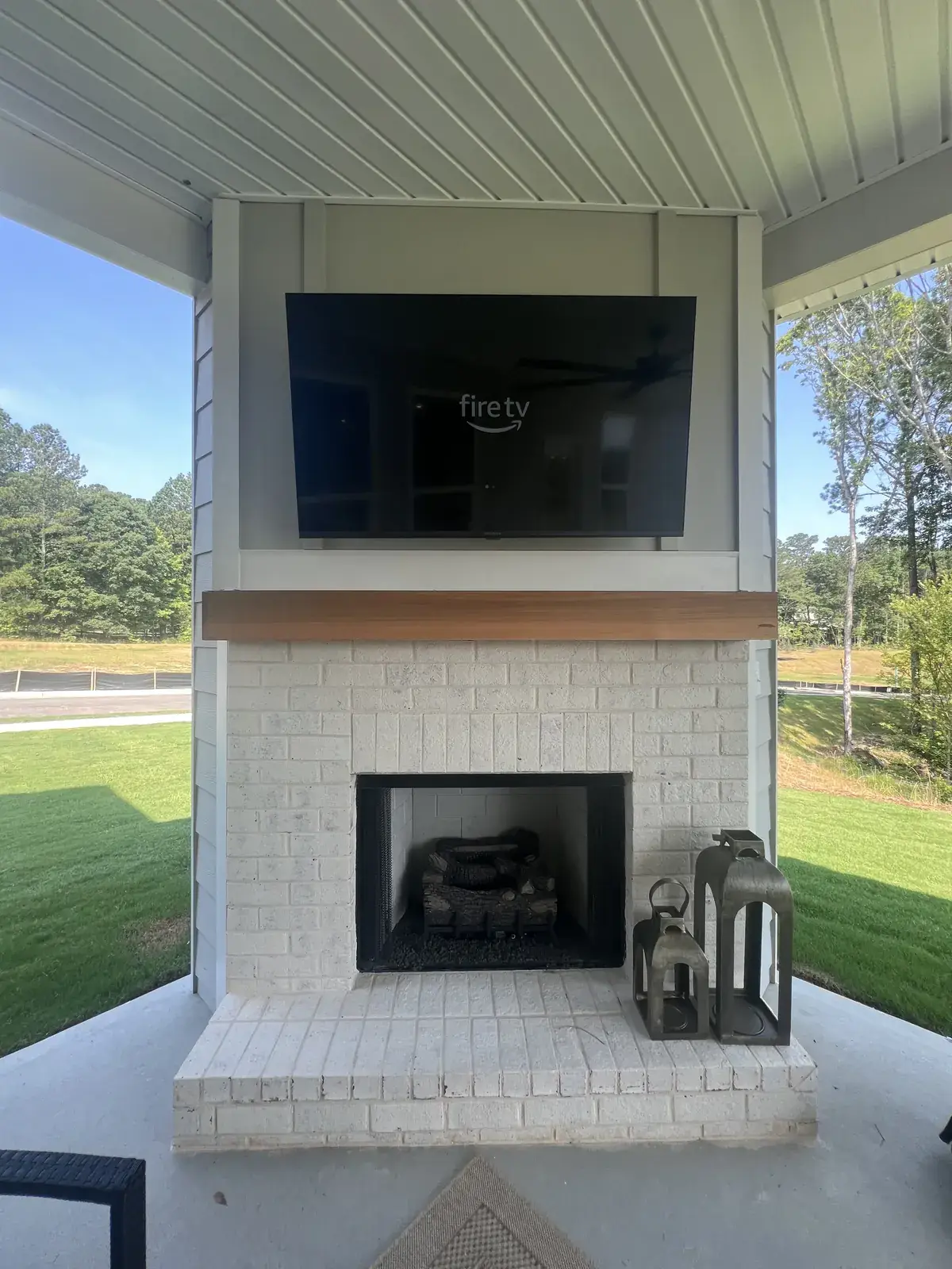 The same porch TV above the painted-brick fireplace, seen straight on