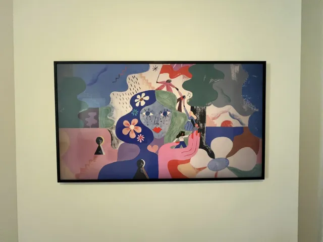 A Samsung Frame TV in Art Mode showing an abstract floral print on a cream wall