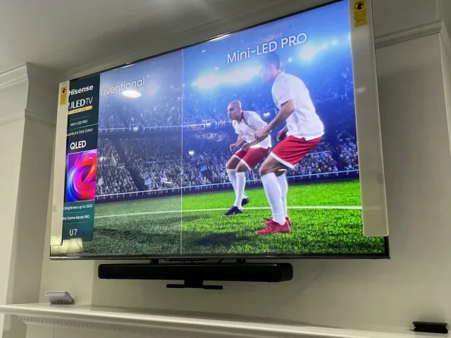 A Hisense mini-LED TV mounted inside a white paneled alcove, showing a soccer broadcast