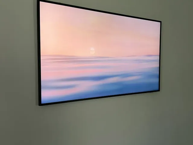 A TV in Art Mode showing a pastel sky on a gray wall