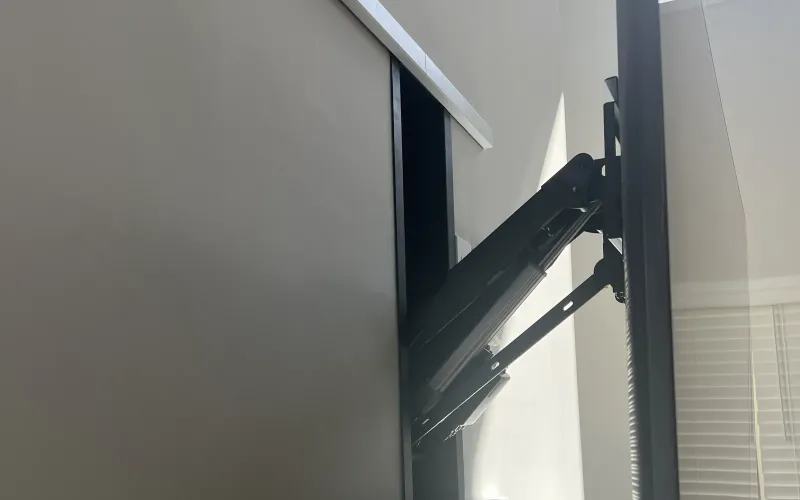 A full-motion wall mount's arm extended from the wall, holding a TV angled away from it