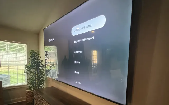 A very large TV mounted low above a wooden console in a living room