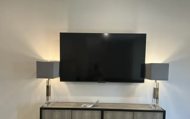 A flat-mounted TV centered above a sideboard between two table lamps